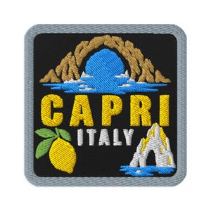 Puede incluir: Un parche bordado cuadrado con fondo negro y borde gris. Presenta un limón amarillo con hojas verdes, un mar azul, un arco de roca color canela y una formación rocosa blanca. El texto CAPRI es amarillo y ITALY es de color blanco.
