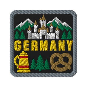 May include: A square embroidered patch with a black background and a gray border. It features a white castle, green pine trees, and snow-capped mountains. The word GERMANY is stitched in yellow. Below are a yellow beer stein and a brown pretzel.