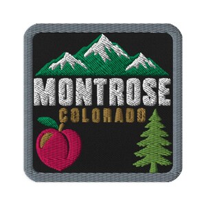 May include: A square embroidered patch with a black background and a gray border. It features green mountains with white snow caps, the white text MONTROSE, the gold text COLORADO, a pink peach with a green leaf, and a green pine tree illustration.