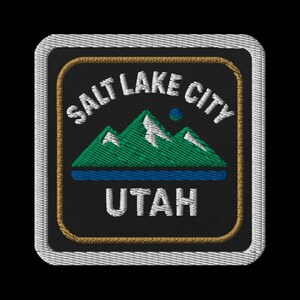 Peut inclure: Écusson brodé avec l'inscription "SALT LAKE CITY UTAH" au-dessus d'une chaîne de montagnes vertes et d'eau bleue. Le patch a un fond noir, une bordure dorée et un bord cousu blanc, idéal pour les vêtements.