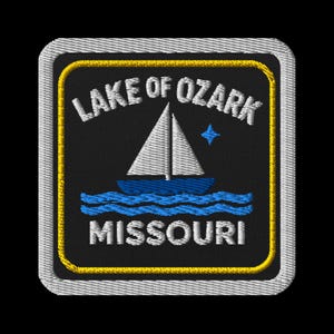Puede incluir: Parche bordado con las palabras "Lake of Ozark Missouri", un velero azul y agua azul. El parche tiene un fondo negro, un borde amarillo y un borde cosido blanco.