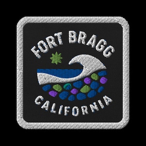 May include: Embroidered patch with the text "FORT BRAGG CALIFORNIA" in white. The patch features a wave, a star, and colorful stones on a black background, framed by a white border.