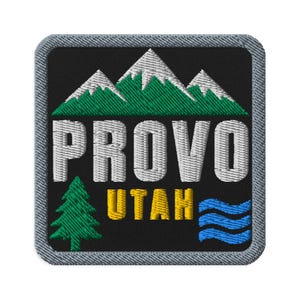 May include: A square embroidered patch with a black background and a gray border. It features white mountain peaks above green pine trees, the white text PROVO, the yellow text UTAH, a green pine tree on the left, and blue wavy lines on the right.