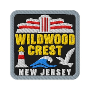 Puede incluir: Un parche bordado cuadrado con borde gris sobre fondo negro. Presenta un faro blanco y rojo, una ola azul, una gaviota blanca y una estructura arquitectónica blanca. El texto dice WILDWOOD CREST y NEW JERSEY.