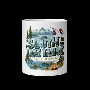 May include: White ceramic mug featuring a colorful illustration of South Lake Tahoe, California. The design includes text, mountains, a lake, and images of outdoor activities like skiing, kayaking, and biking. The mug is a standard size.