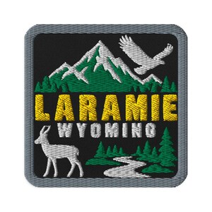 May include: A square embroidered patch with a black background featuring a white mountain range, a flying eagle, and a green forest. The text LARAMIE is in yellow, WYOMING is in white, with a white pronghorn and a winding river at the bottom.