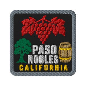 Pode incluir: Um emblema bordado quadrado com fundo preto e borda cinza. Apresenta um cacho de uvas vermelho, uma árvore verde e um barril de madeira marrom. O texto branco diz PASO ROBLES e o texto amarelo abaixo diz CALIFORNIA.