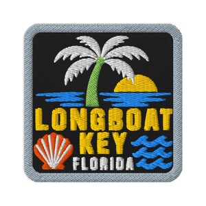 Peut inclure: Un écusson brodé carré sur fond noir représentant un palmier blanc, un soleil jaune et de l'eau bleue. Le texte indique LONGBOAT KEY FLORIDA en jaune et blanc. Un coquillage orange et des vagues bleues ornent les coins inférieurs.