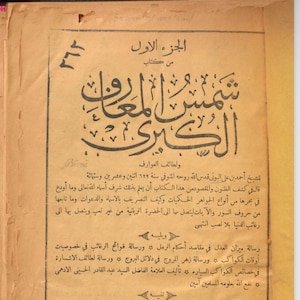 Puede incluir: Una página de un libro antiguo con texto árabe en tinta negra sobre un fondo de papel amarillento. El texto incluye el título "Shums al-Ma'arif al-Kubra" (El Gran Sol del Conocimiento) y el nombre del autor, "Ahmad ibn Ali al-Buni".