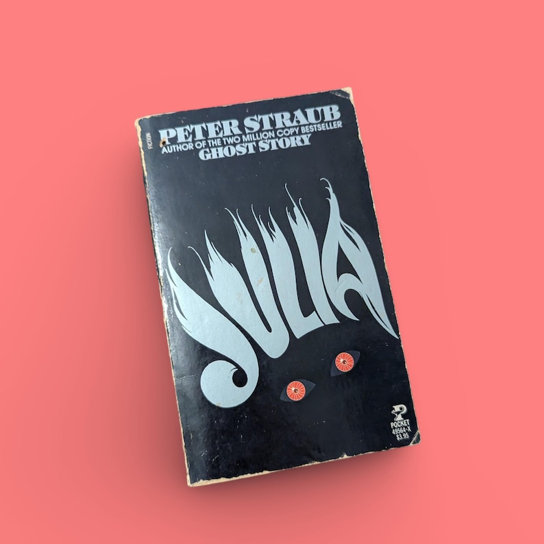 May include: A black paperback book with the title "Julia" in silver lettering. The author is Peter Straub, author of the two million copy bestseller "Ghost Story".