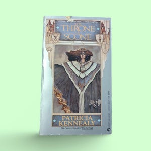 May include: A book cover with a silver background and a woman in a blue and white robe. The title of the book is "The Throne of Scone" by Patricia Kennealy. The book is the second novel of The Keltiad.
