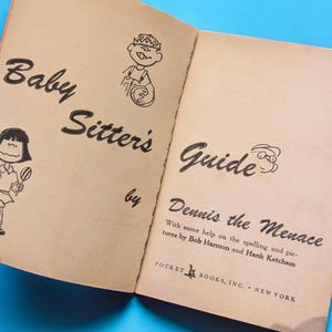 May include: A vintage paperback book titled "Baby Sitter's Guide by Dennis the Menace" with illustrations of children. The book cover is beige with black text and illustrations.