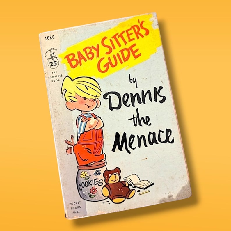 May include: A vintage paperback book titled "Baby Sitter's Guide by Dennis the Menace". The cover features a cartoon illustration of Dennis the Menace standing on a cookie jar with a teddy bear.