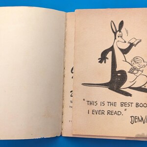 May include: An open book with a black and white illustration of a kangaroo reading a book to a small child. The text on the page reads "This is the best book I ever read."  Dennis.