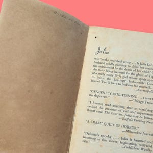 May include: A close-up of a book page with the title "Julia" and text about a haunted house. The text includes quotes from various publications, including "Cosmopoli", "Chicago Tribune", "Buffalo Evening News", "Milwaukee Journal", and "Publishers Weekly".
