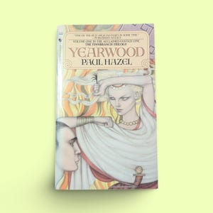 Puede incluir: Una portada de libro con una ilustración de fantasía de una mujer con el pelo largo y rubio y un hombre con barba. El título del libro es "Yearwood" y el autor es "Paul Hazel".