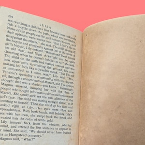 May include: A close-up of a book page with text about a child riding a bicycle. The text is from a novel called "Julia" and includes the quote "But I don't like to disappoint the others."