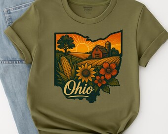 May include: Olive green t-shirt with a graphic depicting the state of Ohio, showcasing a farm scene with a barn, corn, sunflowers, and the word "Ohio". The shirt has rolled-up sleeves and is made of a soft material.