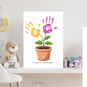 Puede incluir: Un fondo blanco con una impresión de arte de huella de mano de una planta con flores rosas y amarillas. El texto "Tiny prints, big blossoms!" está debajo de la planta.