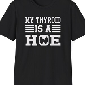 May include: Black t-shirt with the white text "MY THYROID IS A HOE". The text is in a bold, sans-serif font. The shirt is a crew neck style.