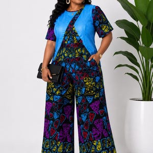 May include: A vibrant jumpsuit featuring a blue bodice with a geometric design and short sleeves. The jumpsuit's wide-leg pants showcase a colorful, patterned print with red, yellow, blue, and purple shapes. A black clutch is held in the hand.