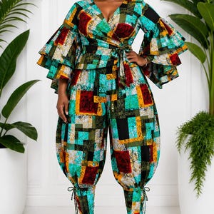 May include: A vibrant, geometric-patterned jumpsuit with a wrap-style top and wide, ruffled sleeves. The high-waisted pants have a unique, gathered design at the ankles. The color palette includes teal, red, yellow, and black. The model is wearing black heels.