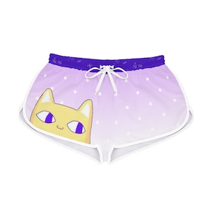 May include: Light purple shorts with a cat graphic. The shorts feature a gradient design with white polka dots and a white drawstring. The cat has yellow fur and purple eyes. The trim is white.