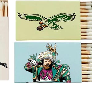 May include: Matchboxes with various designs. One features football players, another an eagle with a football, and a third depicts a man in ornate attire. The fourth box displays the word "Eagles" in green.