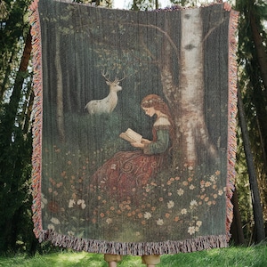 100 percent cotton woven wall hanging tapestry or blanket featuring a medieval maiden reading a book in a forest surrounded by flowers while a majestic white stag watches over her