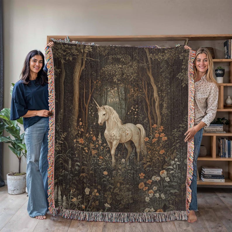 K&ouml;nnte beinhalten: Eine Wanddecke aus Gobelin mit einem wei&szlig;en Einhorn, das in einem dunklen Wald mit gr&uuml;nem und braunem Laub steht. Das Einhorn hat ein goldenes Horn und ist von Blumen umgeben.