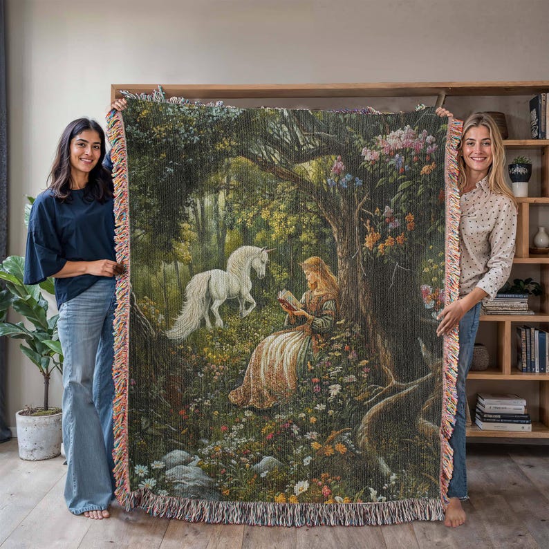 Peut inclure: Une tapisserie repr&eacute;sentant une licorne blanche et une femme lisant un livre dans un d&eacute;cor de for&ecirc;t. La tapisserie est de couleur verte, marron et rose avec des d&eacute;tails floraux.