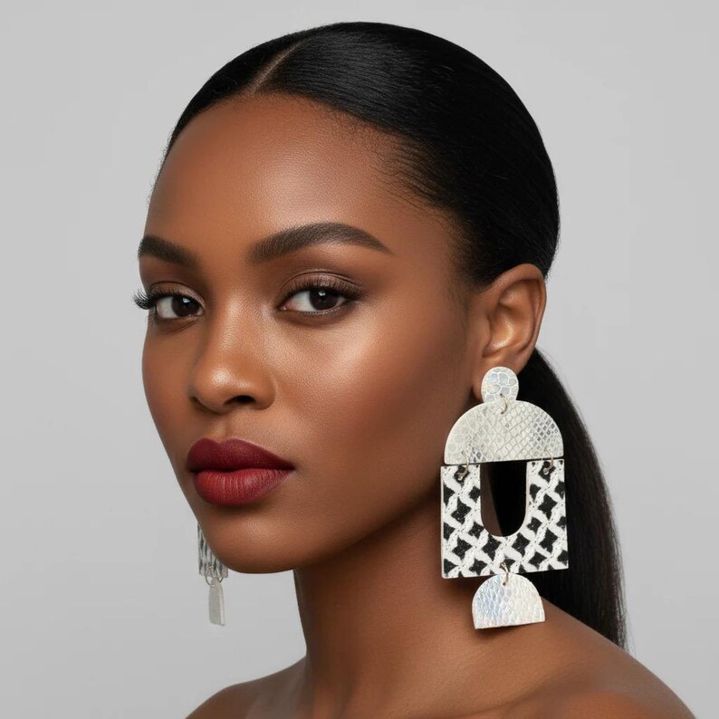 Pode incluir: Brincos geom&eacute;tricos prateados e pretos com um padr&atilde;o texturizado. Os brincos t&ecirc;m um design arrojado com uma mistura de formas, incluindo um semic&iacute;rculo, um ret&acirc;ngulo e um semic&iacute;rculo menor.