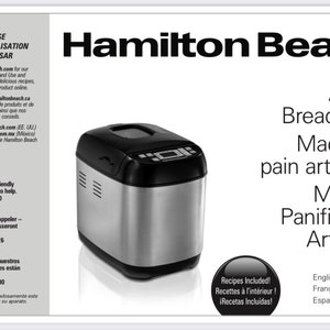 Könnte beinhalten: Eine silberne Hamilton Beach Artisan Breadmaker Maschine mit schwarzem Deckel und digitalem Display. Die Maschine steht auf einer weißen Oberfläche mit einer Spiegelung. Der Text "Rezepte enthalten!" befindet sich in einem schwarzen Kreis unter der Maschine.