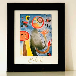 Peut inclure: Impression encadrée d'art abstrait avec des formes géométriques et une figure centrale orange et noire. L'œuvre, signée "Miró", est encadrée dans un cadre noir, idéale pour la décoration intérieure.