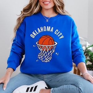 May include: A royal blue sweatshirt with the text "OKLAHOMA CITY" in white with a basketball going through a hoop in the centre of the text.