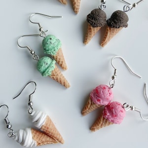 Ice cream dangle earrings on a white background. Strawberry icecream, chocolate ice cream, softserve icecream, vanilla ice cream and mint chocolate chip icecream. Scooped ice cream cones and soft serve ice cream cones.