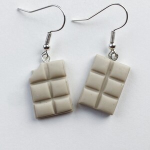 White chocolate bar dangle earrings. Left chocolate bar is missing a tiny bite of the chocolate in the top corner.