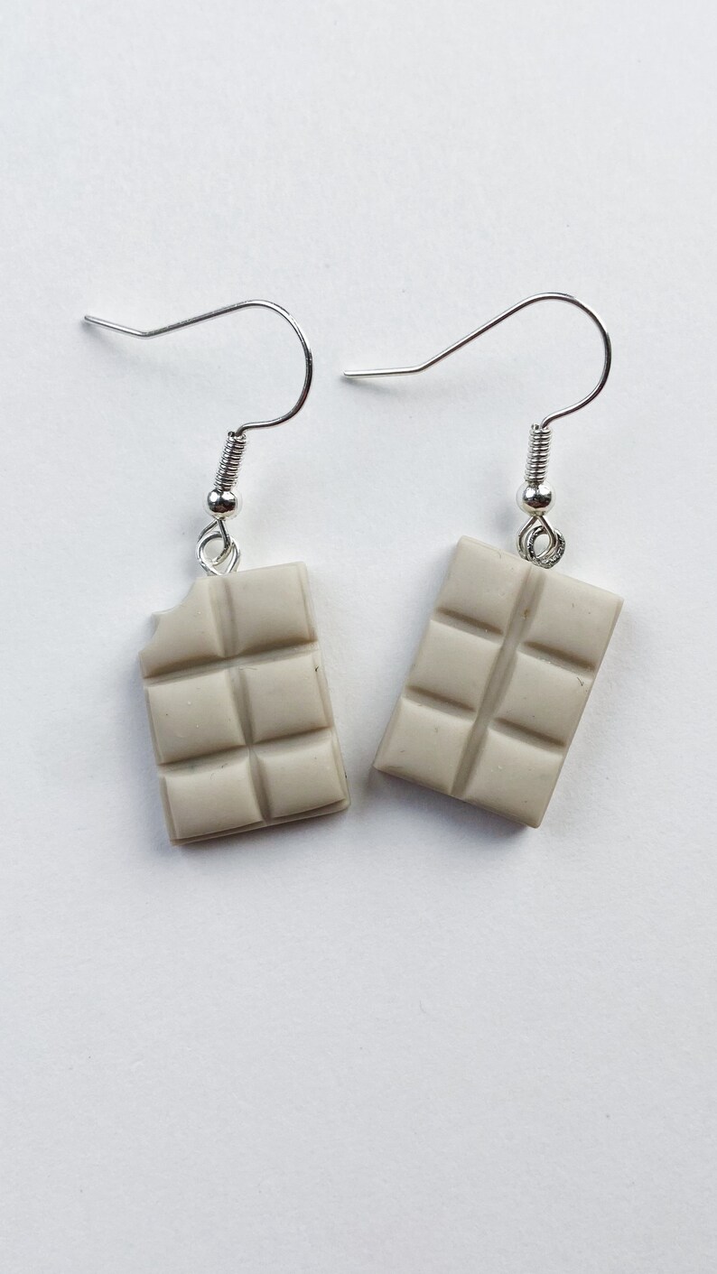 White chocolate bar dangle earrings. Left chocolate bar is missing a tiny bite of the chocolate in the top corner.