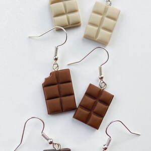 Chocolate bar earrings stacked
white background
White chocolate bars
Milk chocolate bars
Dark chocolate bars
Single small bite out of the chocolate bars