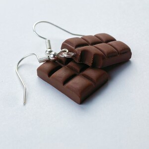 Milk chocolate bar earrings stacked on top of eachother. A bite has been taken out of the top chocolate bar earring.