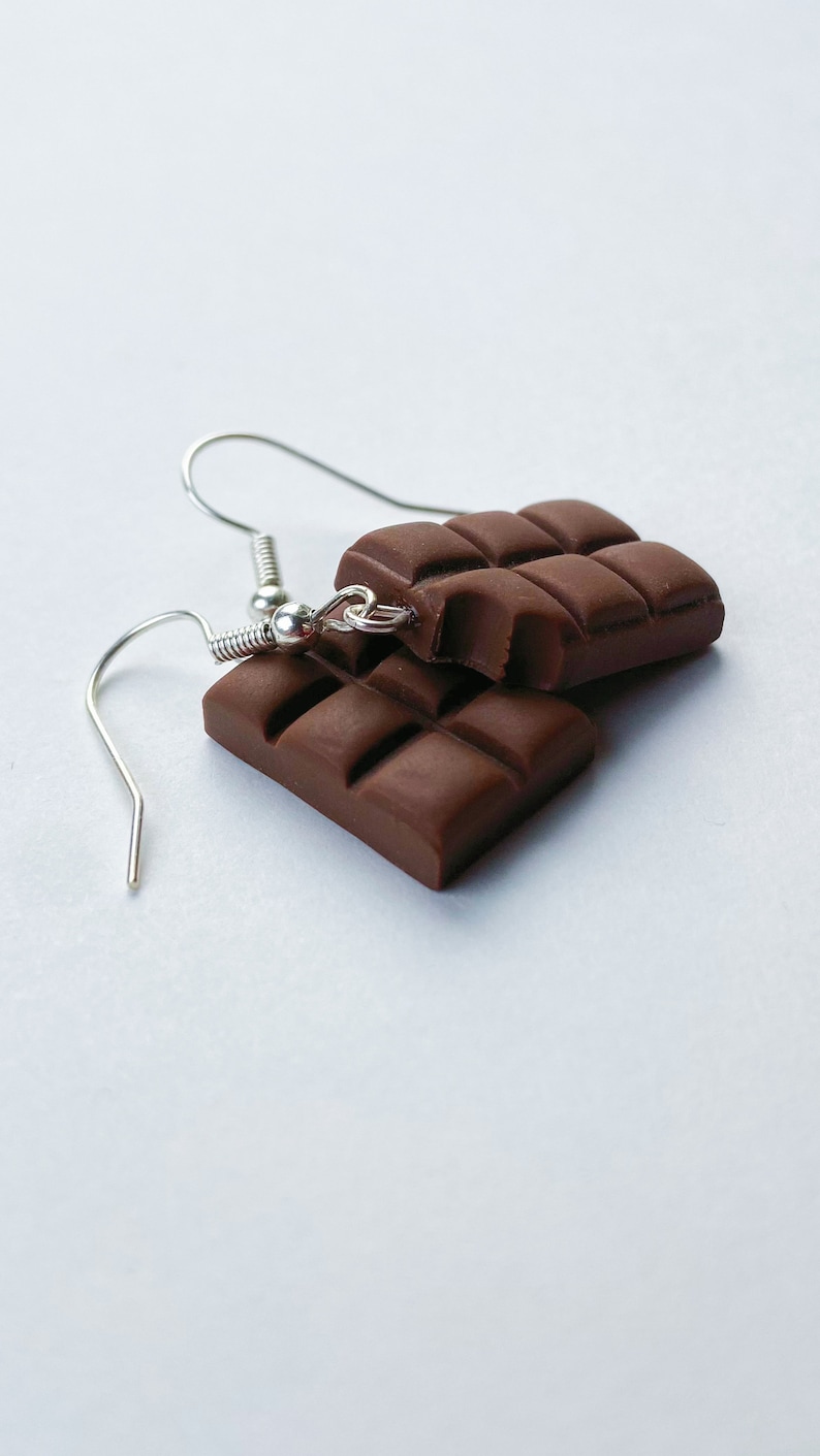Milk chocolate bar earrings stacked on top of eachother. A bite has been taken out of the top chocolate bar earring.