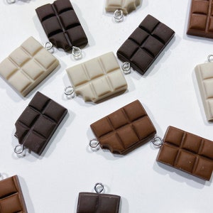 Collection of chocolate bar charms. Some chocolate bars are missing a tiny bite of chocolate in the corner. 6 white chocolate bars, 5 dark chocolate bars, 5 milk chocolate bars.