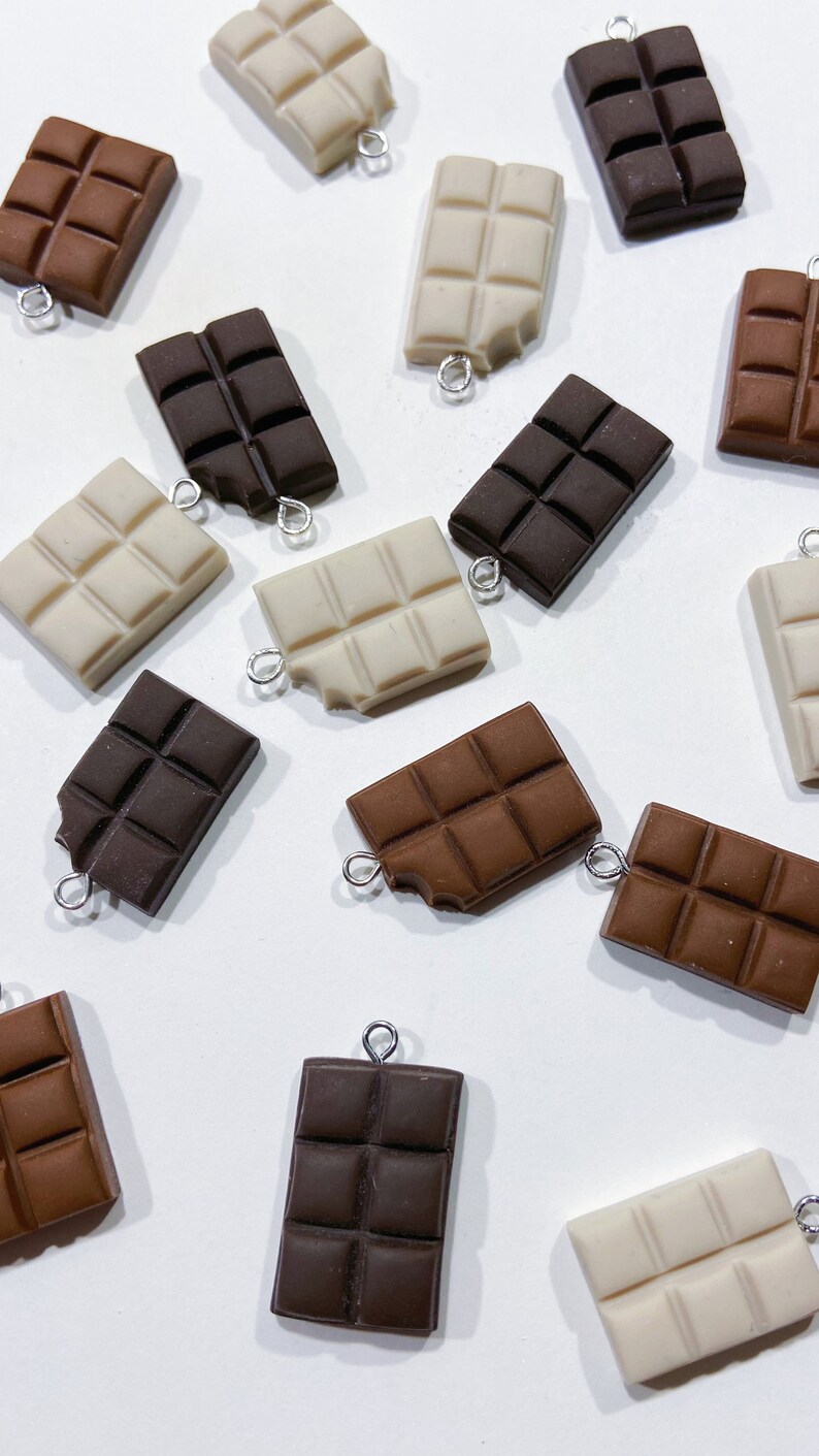 Collection of chocolate bar charms. Some chocolate bars are missing a tiny bite of chocolate in the corner. 6 white chocolate bars, 5 dark chocolate bars, 5 milk chocolate bars.