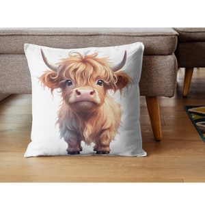 May include: A white pillow with a cute cartoon illustration of a brown and white Highland cow with fluffy hair. The cow is looking directly at the viewer.