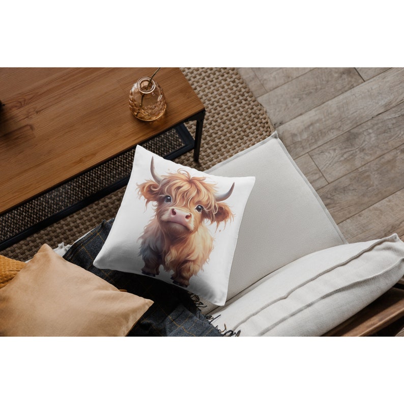 May include: A white throw pillow with a brown and white Highland cow illustration. The cow has long, shaggy hair and is looking directly at the viewer.