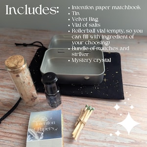 May include: An assortment of spiritual items including a tin, velvet bag, vial of salts, rollerball vial, matches, and a mystery crystal. The image also includes a matchbook labeled "Intention Papers."