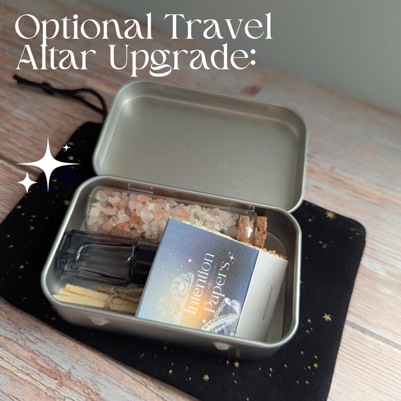 May include: A silver metal tin containing a small glass bottle, a bottle of pink salt, a small booklet labeled "Intention Papers," and wooden sticks. The tin sits on a black cloth with gold stars. Text at the top reads "Optional Travel Altar Upgrade:"