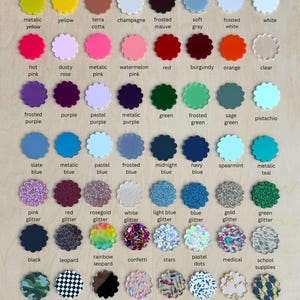 May include: A collection of colorful, scalloped-edge acrylic pieces, each labeled with a color name. Colors range from yellow and pink to blue and green, including glitter and patterned options. The text labels are in a sans-serif font.