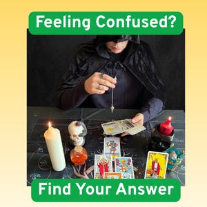 May include: A divination setup featuring a person in a black hooded cloak holding a silver pendulum over a deck of tarot cards. The table includes a white pillar candle, a red candle in a skull holder, a small skull, and a glass vial of orange liquid.