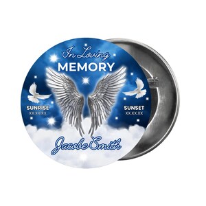 May include: A blue and white memorial button with angel wings, doves, and the text "In Loving Memory" and "Sunrise" and "Sunset". The button also includes the name "Jacobe Smith".